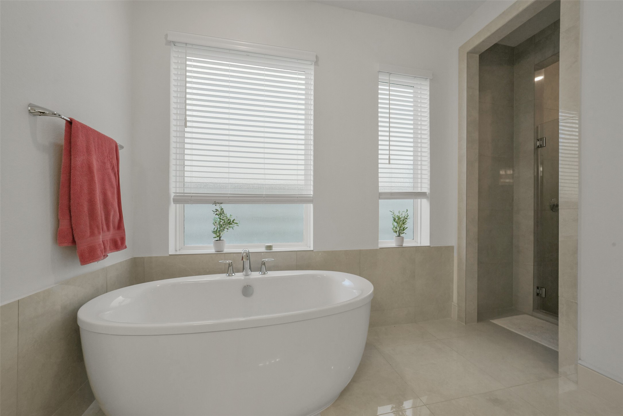 2018 Grove Terrace Lane Manvel, TX 77578 - Photo 26 of 50 Modern bathroom features a sleek freestanding tub, a spacious walk-in shower, rain shower, multiple spa like benches and large windows with blinds for natural light and privacy. The light color palette enhances the room's airy feel.