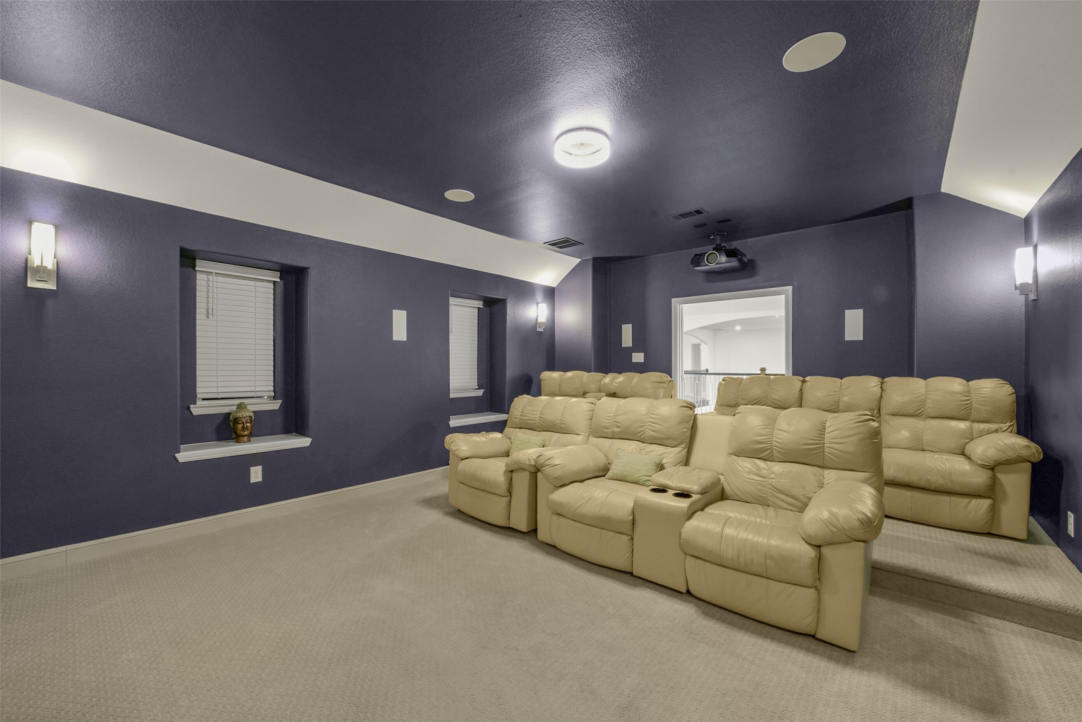 2018 Grove Terrace Lane Manvel, TX 77578 - Photo 31 of 50 Home theater room with plush beige reclining seats arranged in tiered seating (step-up platform), ALL INCLUDED. The walls and ceiling are painted a deep blue, complemented by soft lighting and a ceiling-mounted projector- ALL INCLUDED. It's a cozy space for entertainment enthusiasts.