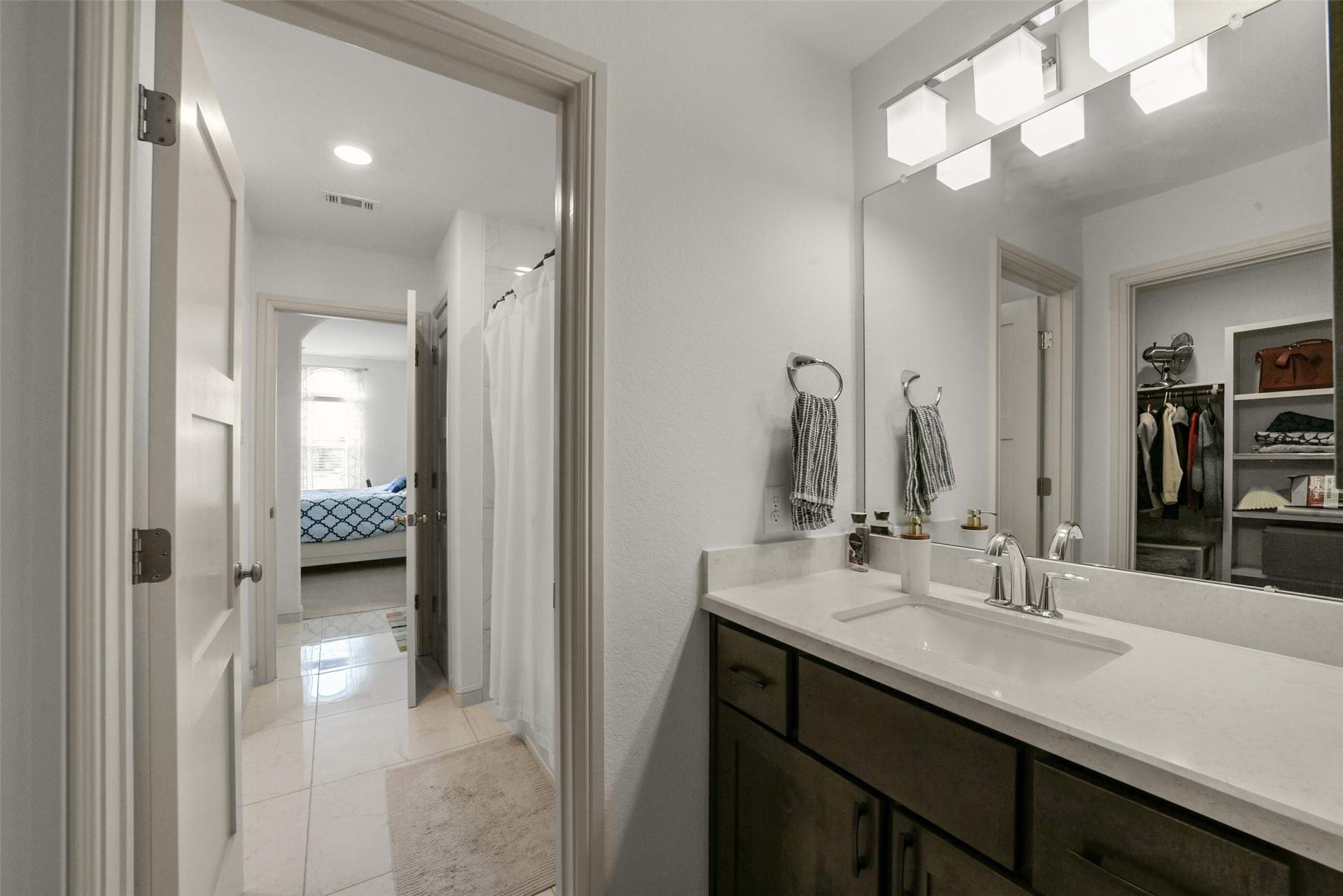 2018 Grove Terrace Lane Manvel, TX 77578 - Photo 34 of 50 Modern bathroom with a sleek vanity, large mirror, and ample lighting. It connects to a bedroom and a walk-in closet, providing convenient access and functionality.