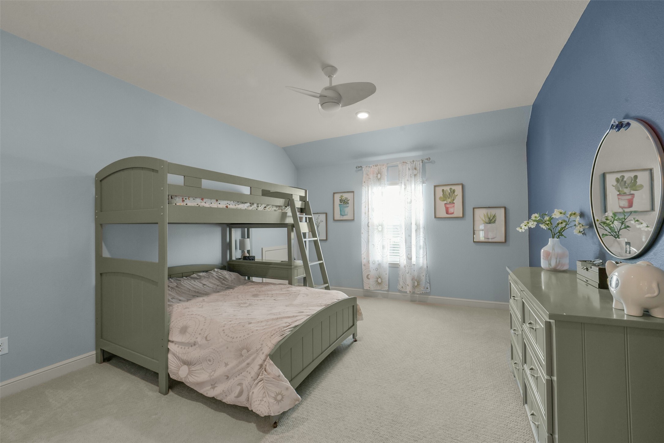 2018 Grove Terrace Lane Manvel, TX 77578 - Photo 36 of 50 A cozy bedroom with soft blue walls and upgraded carpeted flooring. It features a green bunk bed and matching dresser. Natural light streams through a window with sheer curtains, adorned with spacious custom built in closet space. A ceiling fan adds comfort to the serene space.