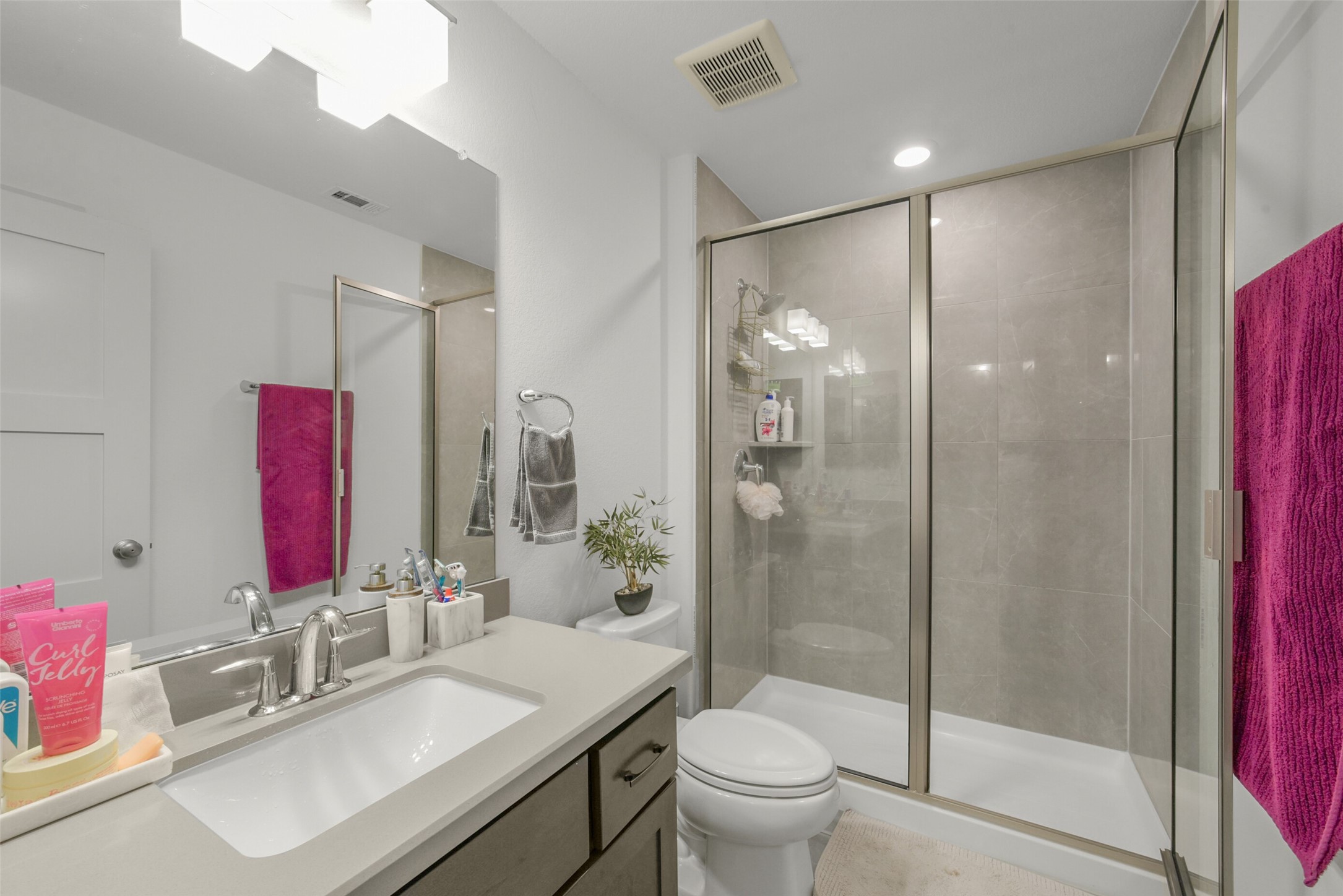 2018 Grove Terrace Lane Manvel, TX 77578 - Photo 38 of 50 This modern bathroom features a spacious glass-enclosed shower with sleek tile, a large vanity with ample countertop space, and contemporary fixtures. Bright lighting and clean lines create a fresh, inviting atmosphere.