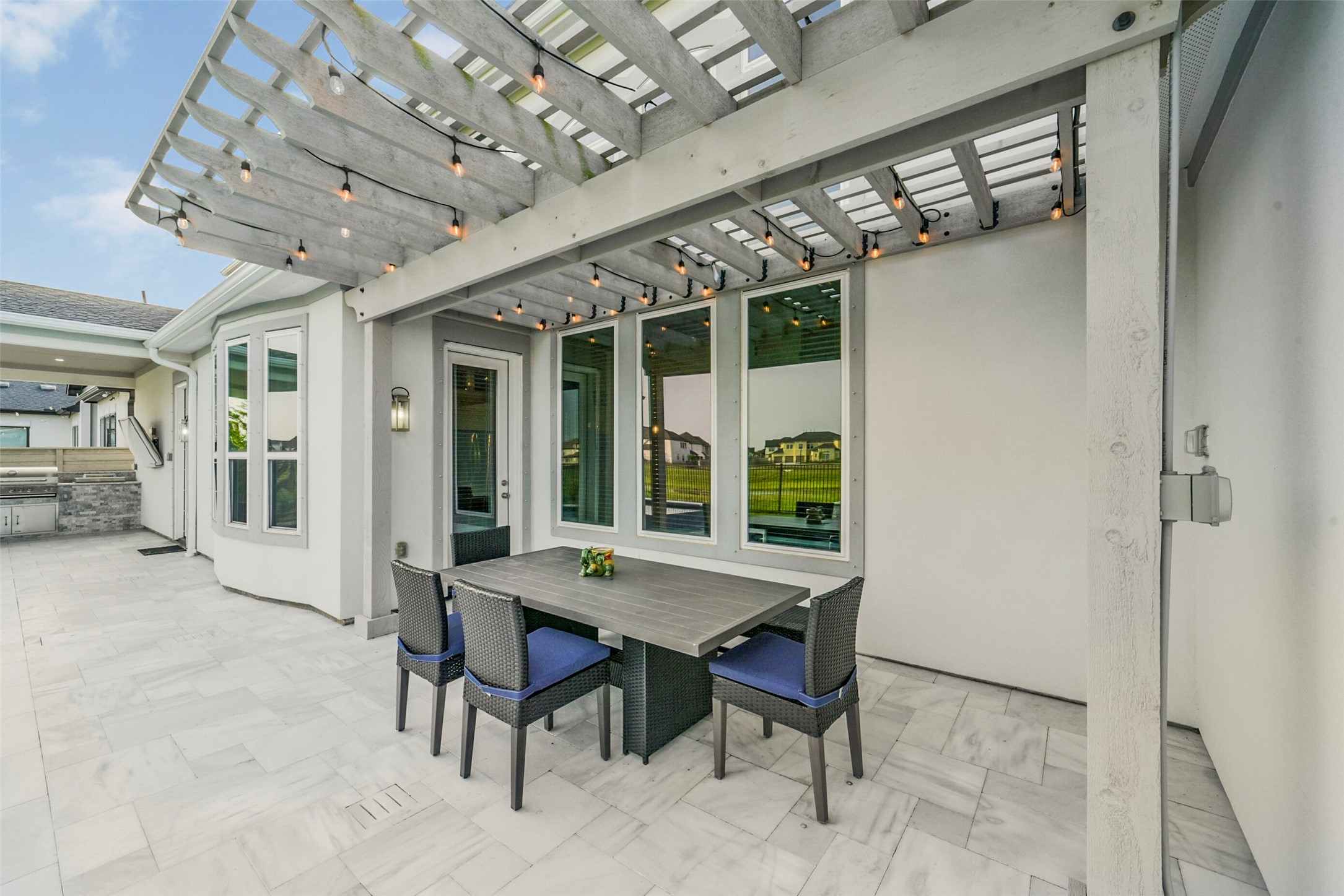 2018 Grove Terrace Lane Manvel, TX 77578 - Photo 40 of 50 Stylish outdoor patio with a pergola adorned with string lights, a modern dining set, and a built-in grill area. The space is perfect for entertaining and enjoying outdoor living.