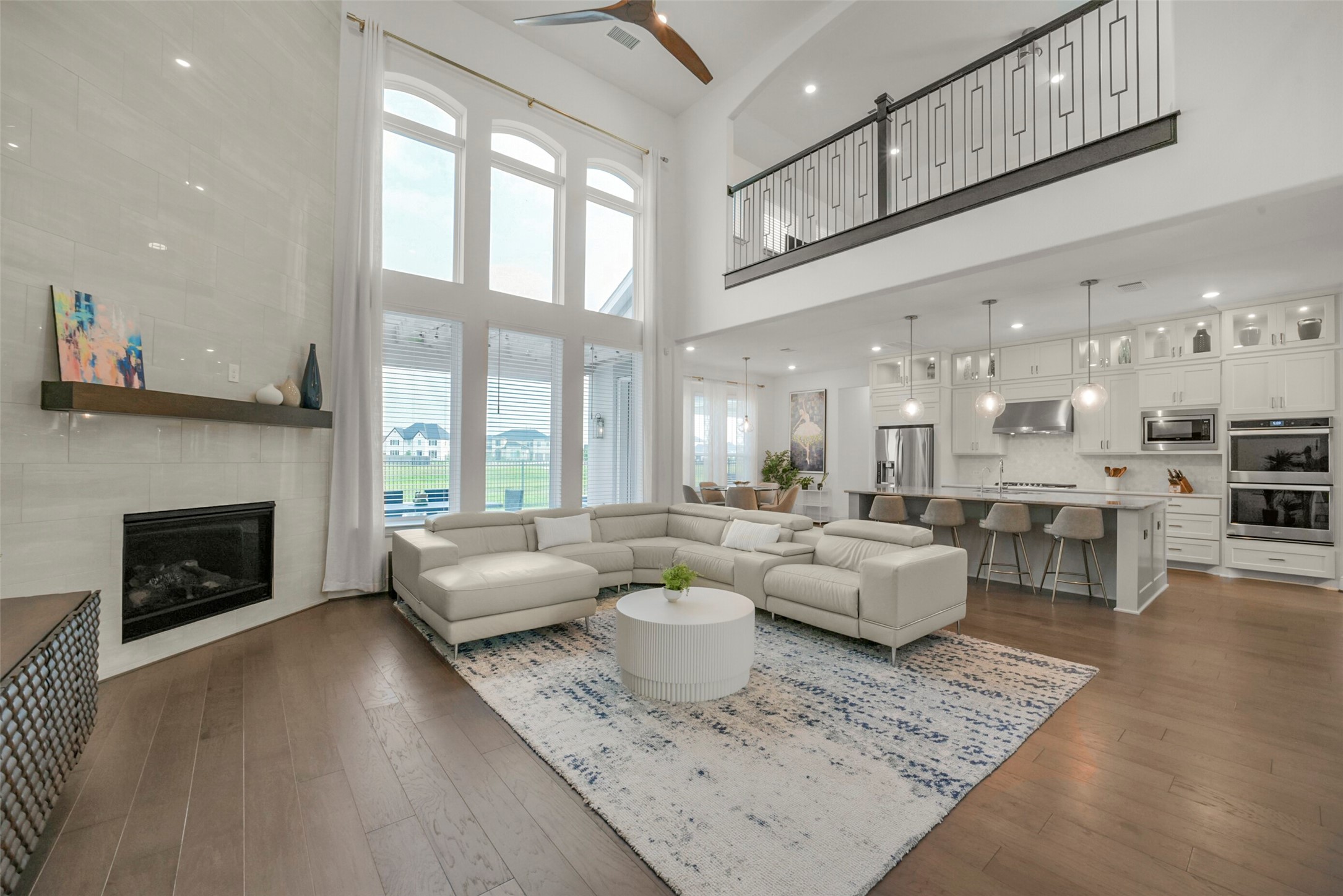 2018 Grove Terrace Lane Manvel, TX 77578 - Photo 50 of 50 This spacious living area features high ceilings and large windows, providing plenty of natural light. The open floor plan connects a modern kitchen with a large island to a cozy living space with a fireplace. The room is elegantly designed with contemporary furnishings and finishes.