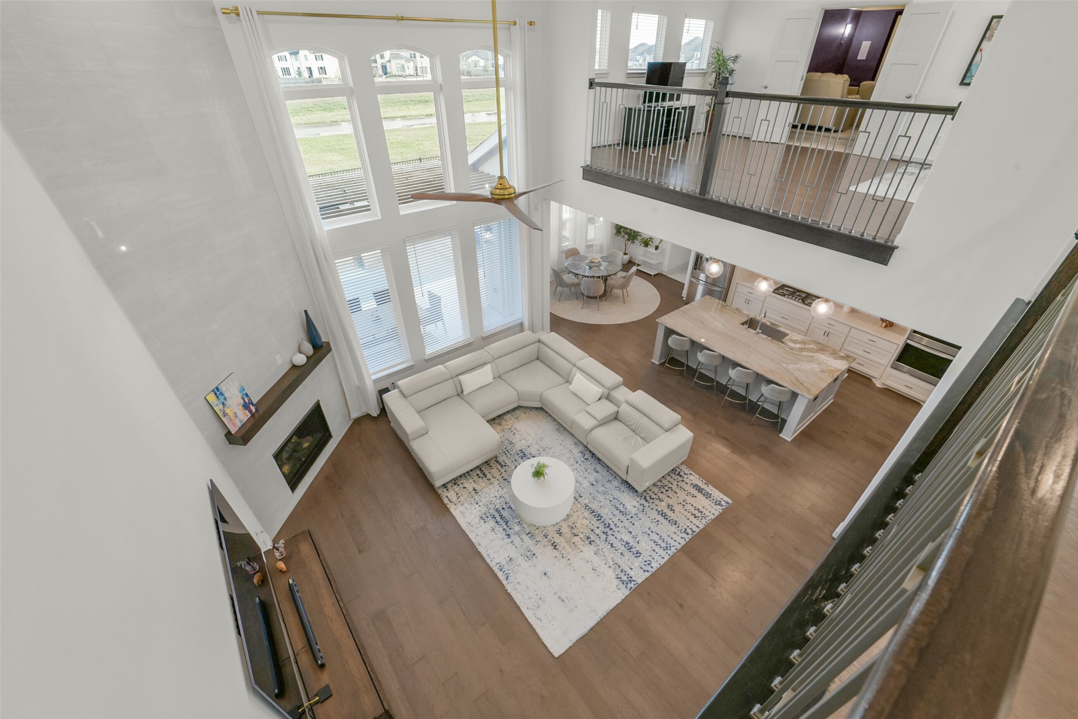 2018 Grove Terrace Lane Manvel, TX 77578 - Photo 5 of 50 This spacious and modern living area features high ceilings with large windows for natural light, a cozy fireplace, and an open layout connecting to the kitchen and dining area. The loft above offers additional living space, enhancing the home's airy and inviting atmosphere.