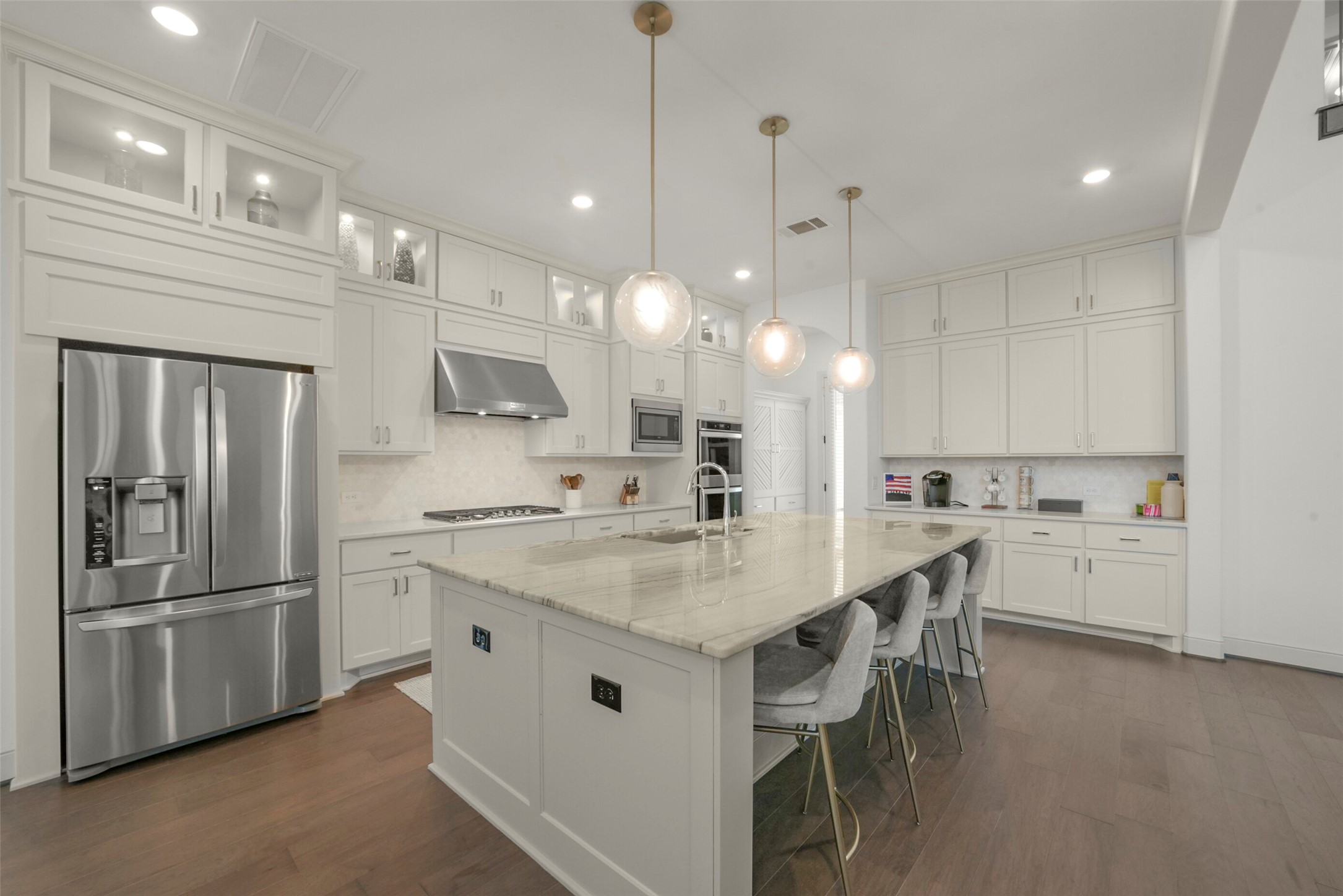 2018 Grove Terrace Lane Manvel, TX 77578 - Photo 6 of 50 Modern kitchen features sleek stainless-steel appliances, an expansive marble island with seating, elegant pendant lighting, and ample cabinet space for storage. The open layout and neutral tones create a bright, inviting atmosphere.