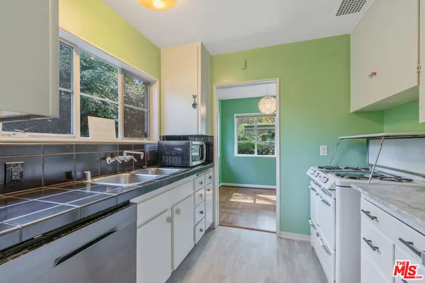 a view of a kitchen with a sink wooden cabinets and a window