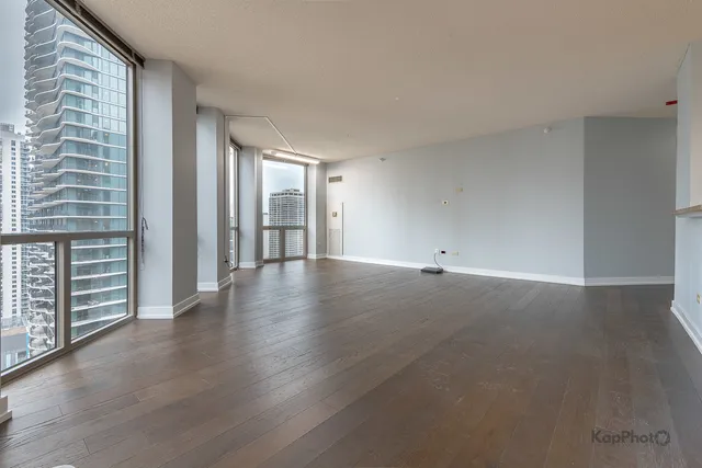 a view of an empty room with a window and wooden floor