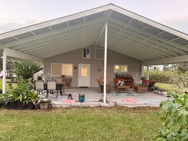 a view of a backyard with table and chairs potted plants and large tree