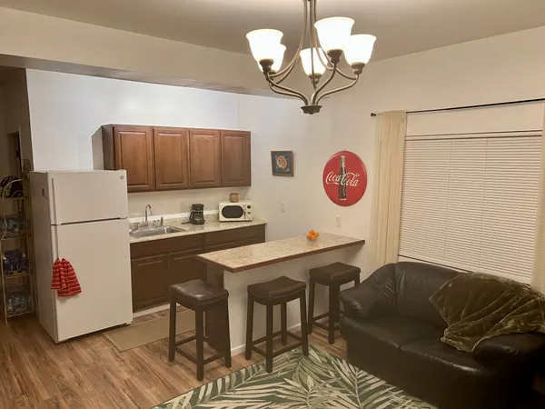 a kitchen with stainless steel appliances granite countertop a refrigerator a sink dishwasher a dining table and chairs with wooden floor