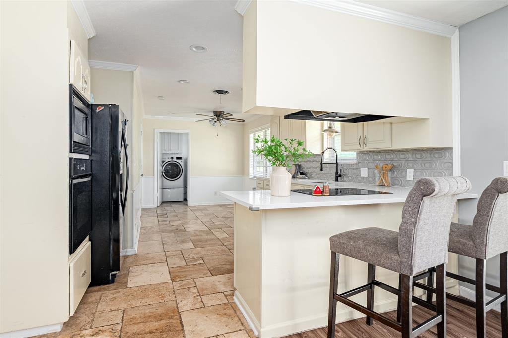 10 Estates Road Lucas, TX 75002 - Photo 10 of 39 Kitchen featuring washer / dryer, a peninsula, black appliances, crown molding, and light countertops