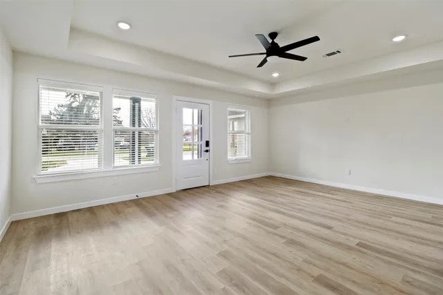 a view of empty room with wooden floor and fan