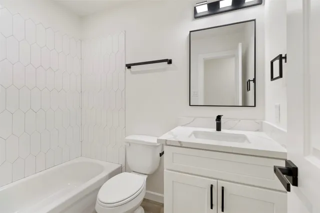 a bathroom with a toilet sink vanity tub and mirror
