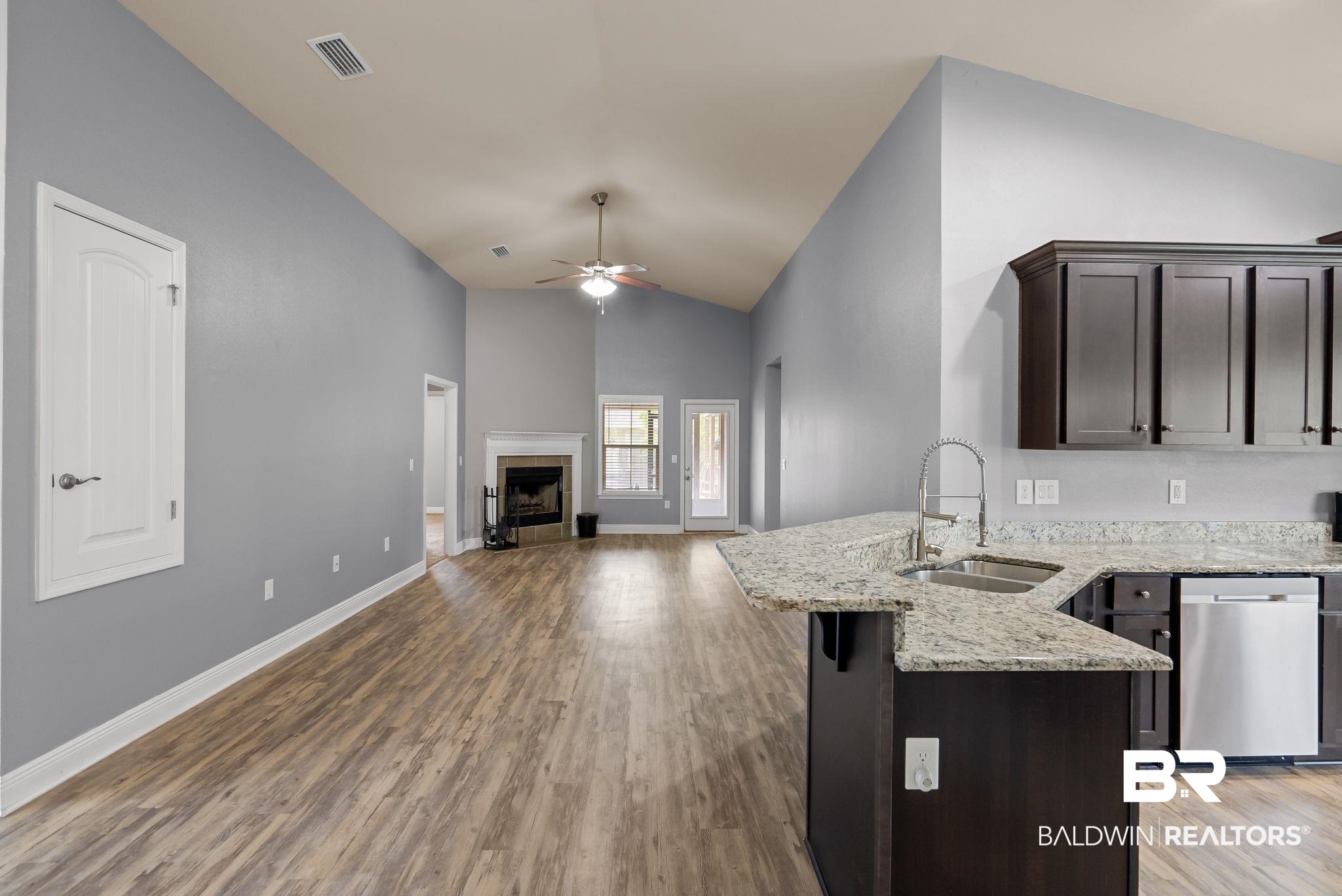 22076 Garland Loop Silverhill, AL 36576 - Photo 8 of 27 Open-concept living area featuring vaulted ceilings, wood-finish flooring, and a fireplace with a white mantel