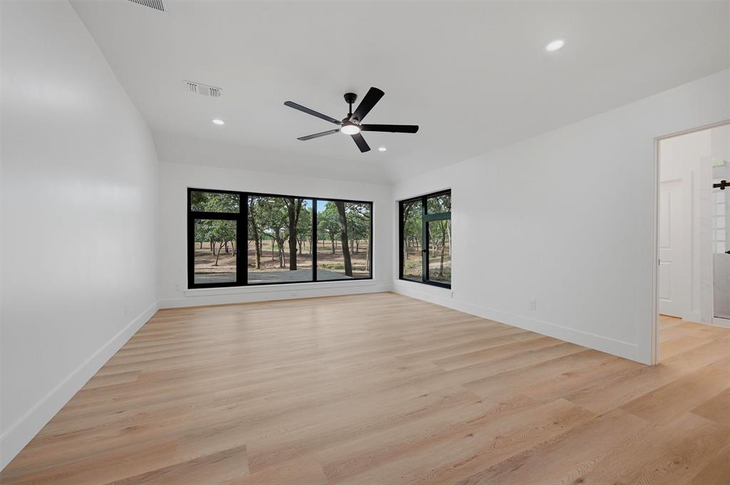 410 Arkansas Road Sadler, TX 76264 - Photo 17 of 40 Spacious room featuring multiple large windows with black frames, wood-finish flooring, a contemporary ceiling fan, and recessed lighting