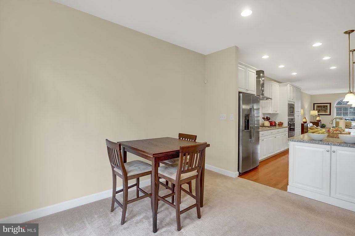 7872 Patterson Way Hanover, MD 21076 - Photo 12 of 26 a kitchen with stainless steel appliances kitchen island granite countertop a refrigerator a stove a sink a table and chairs