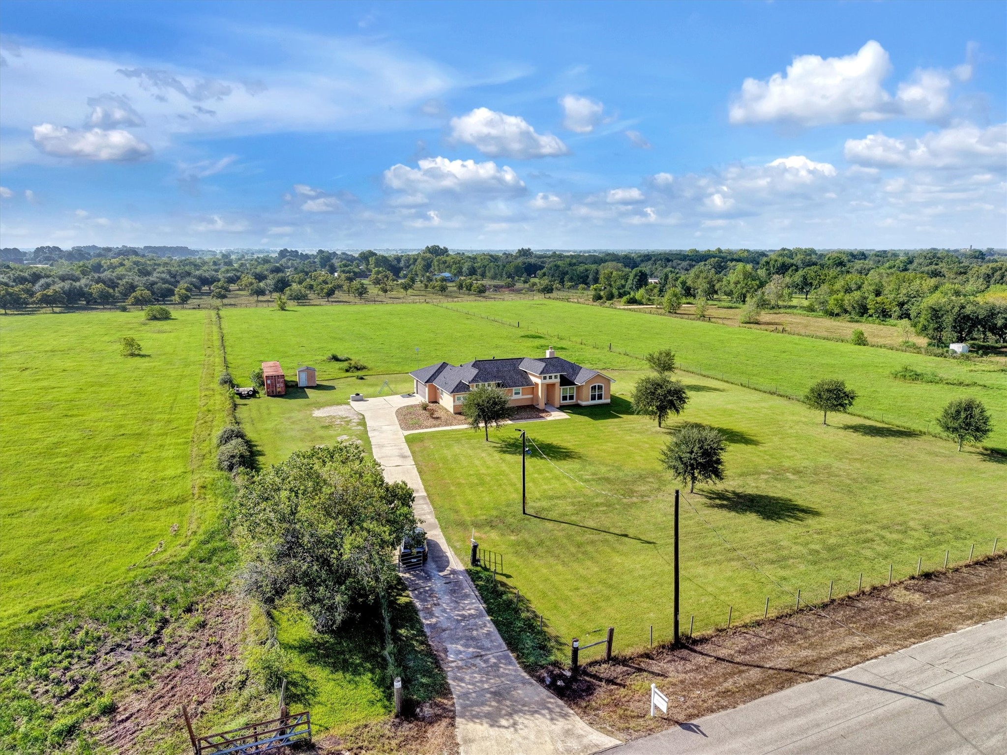 8131 Brinkmeyer Road Needville, TX 77461 - Photo 4 of 49 Expansive country estate featuring a charming single-story home, long driveway, and vast green pastures, offering serene rural living.