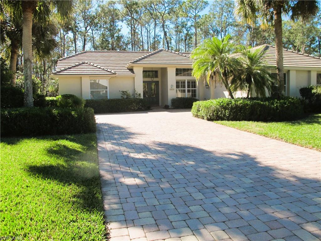 View of front of property with a front lawn, decorative driveway, a tiled roof, and stucco siding