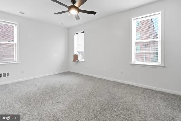 an empty room with chandelier fan and windows