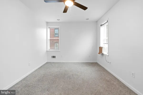 an empty room with a window and a fan