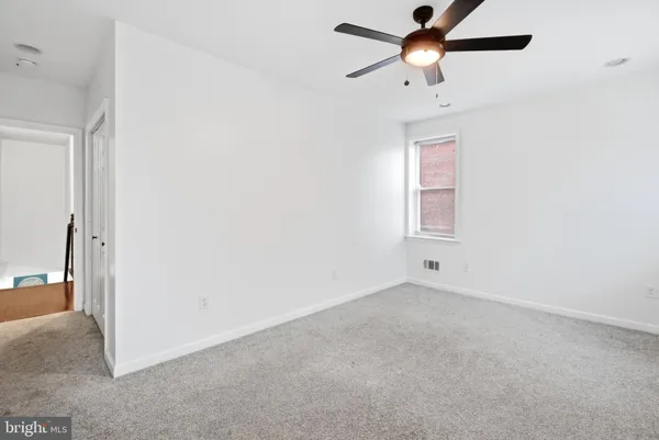 an empty room with a window and a fan