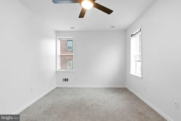an empty room with a window and a fan