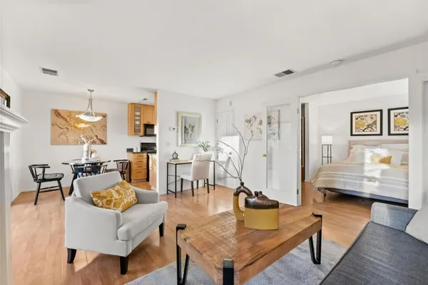 a living room with furniture kitchen view and a wooden floor