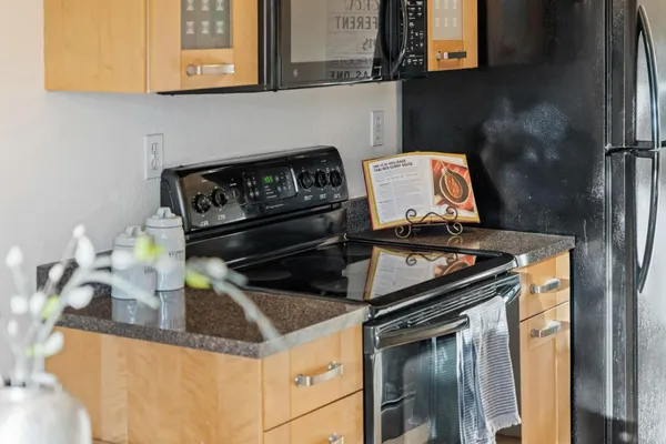 a kitchen with stainless steel appliances granite countertop a stove a microwave and a dining table