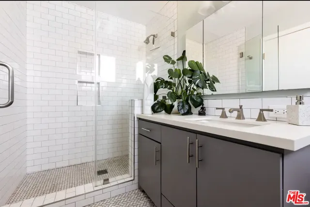 a bathroom with a granite countertop sink a mirror and shower