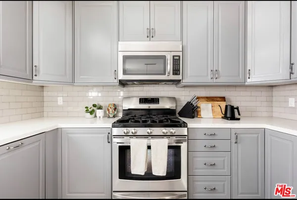 a kitchen with white cabinets and appliances
