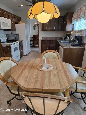 a kitchen with stainless steel appliances granite countertop a sink a stove a dining table and chairs with wooden floor