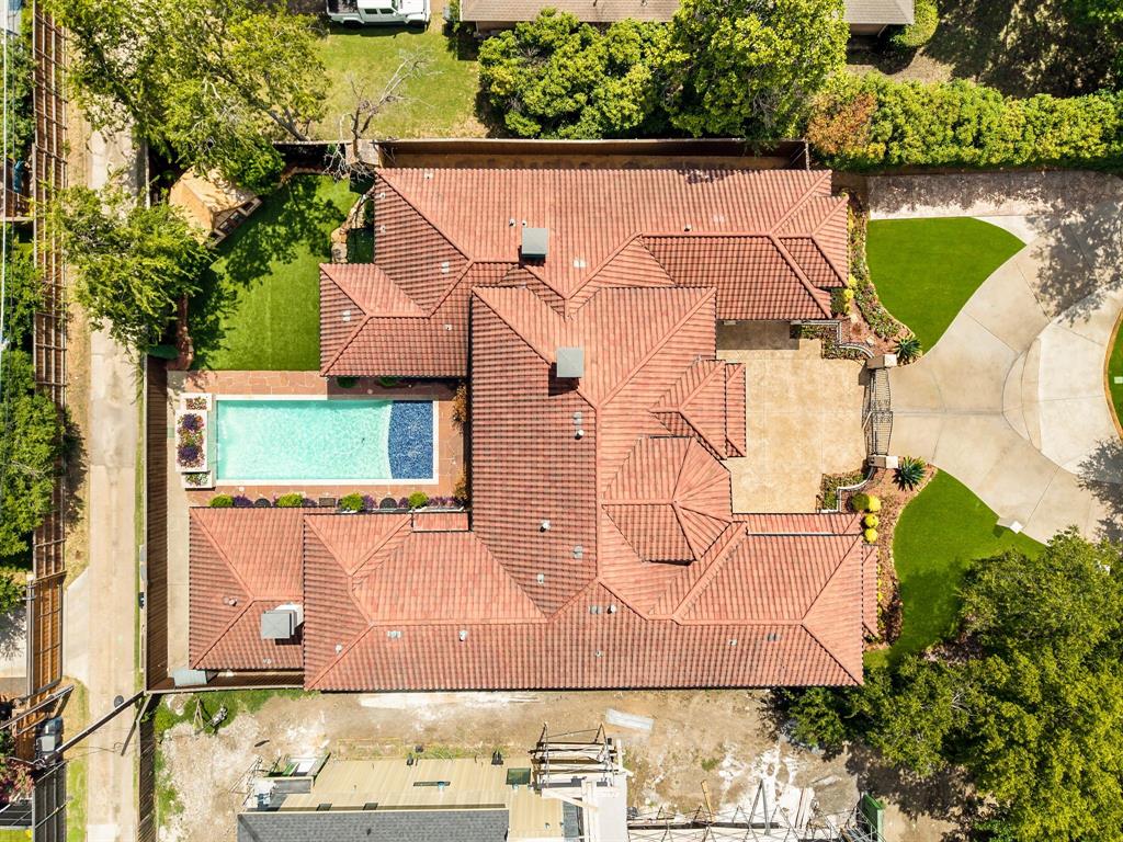 5821 Northaven Road Dallas, TX 75230 - Photo 37 of 40 Tile roof architecture featuring a geometric swimming pool, extensive paved patio, a circular driveway, and manicured landscaping