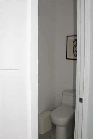 a white toilet sitting next to a white wall