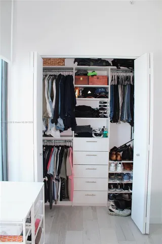 a view of walk in closet with clothes and shoes