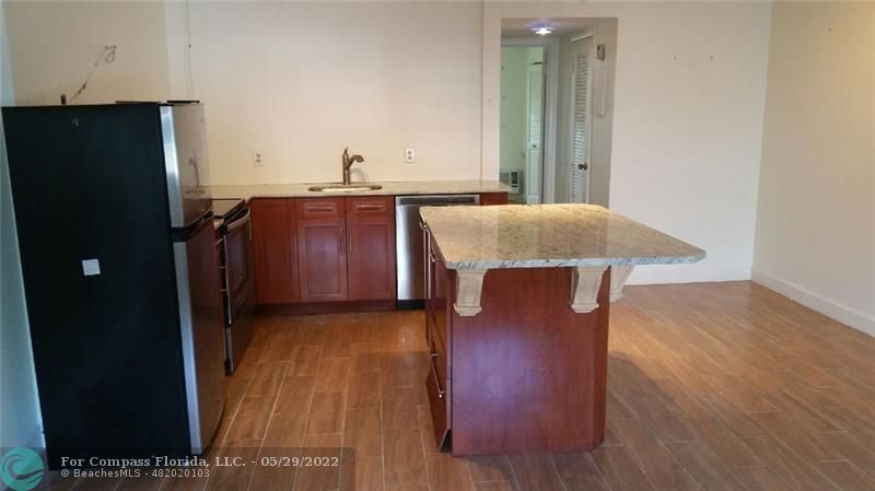 a kitchen with kitchen island wooden floors and refrigerator