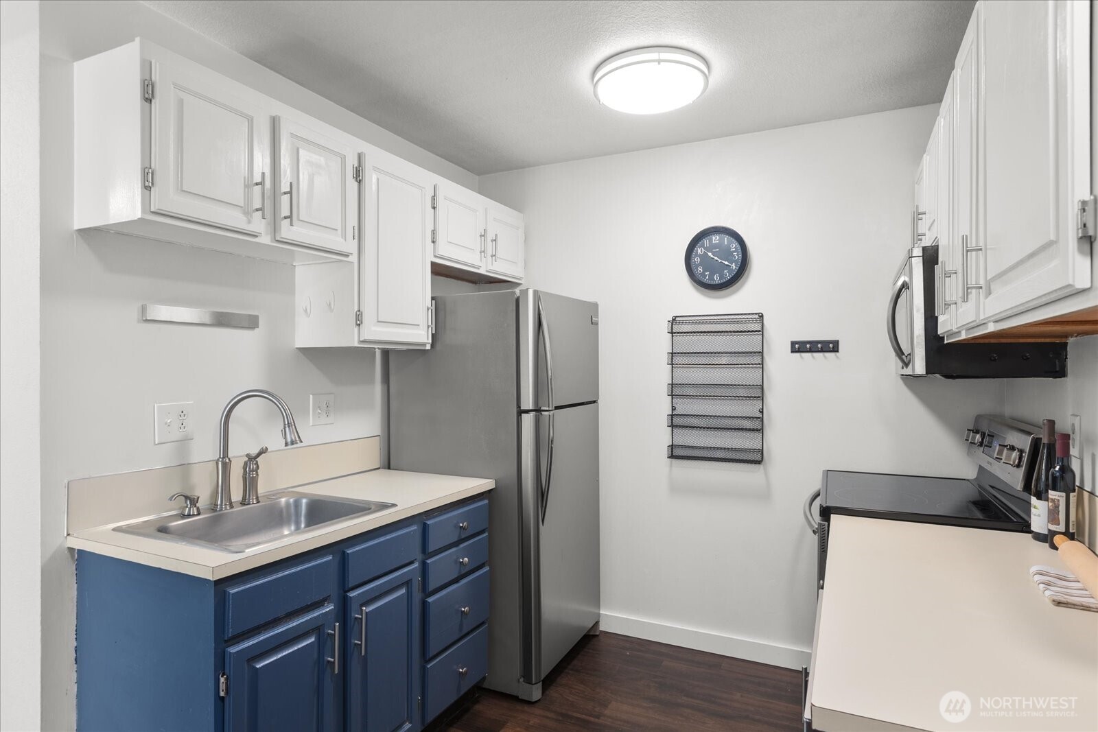 3024 Northeast 143rd Street, Unit 305 Seattle, WA 98155 - Photo 10 of 17 a kitchen with stainless steel appliances a sink cabinets and wooden floor
