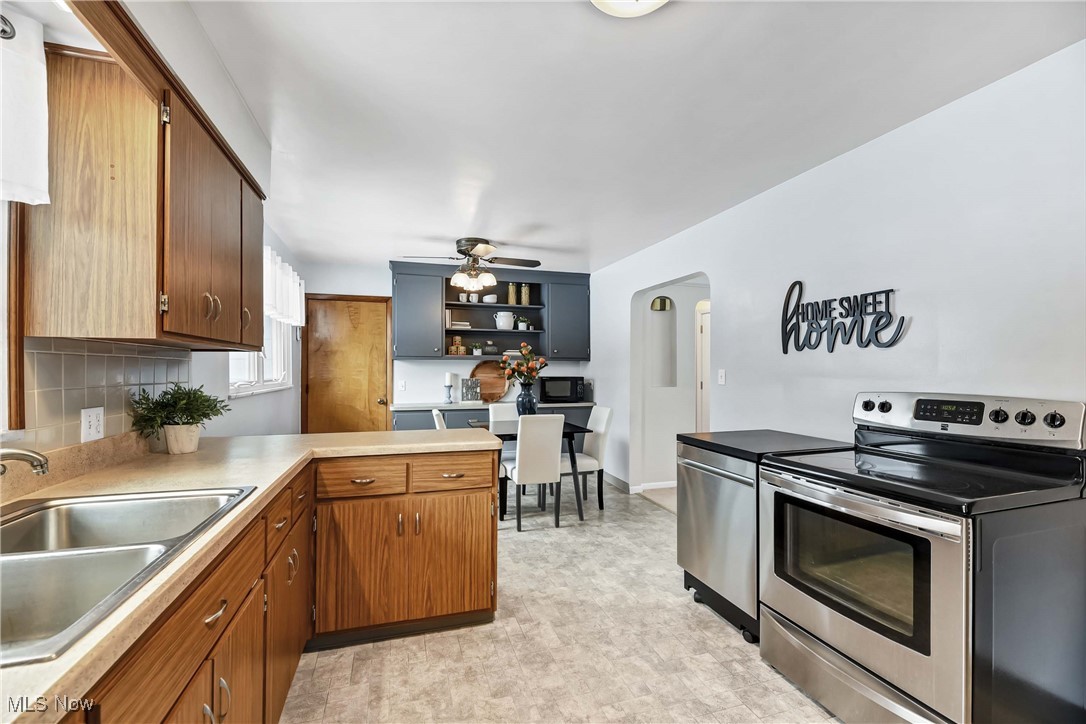 17239 Fowles Road Cleveland, OH 44130 - Photo 13 of 43 Kitchen featuring ceiling fan, sink, backsplash, kitchen peninsula, and stainless steel electric stove