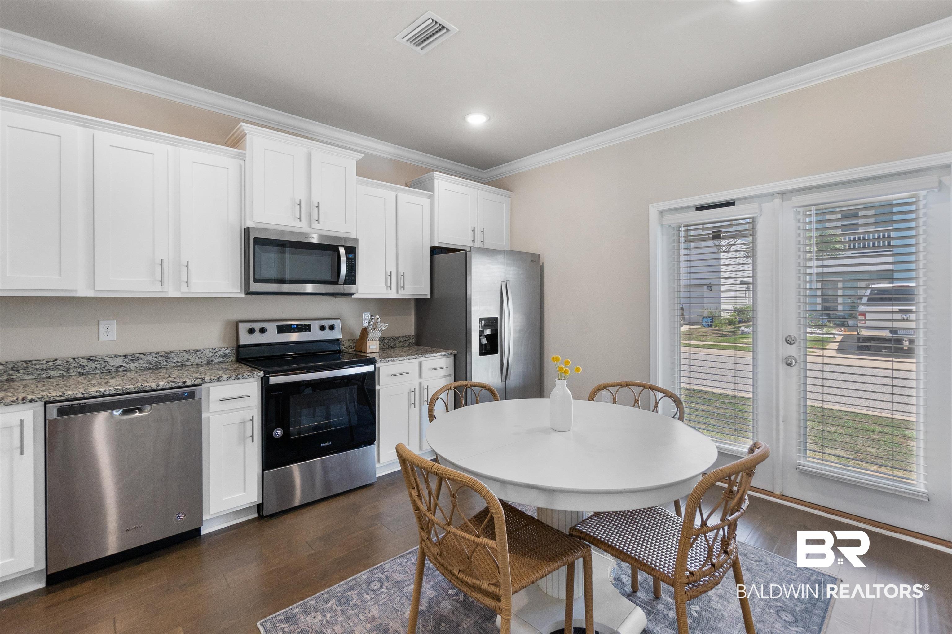 23975 Cottage Loop Orange Beach, AL 36561 - Photo 6 of 23 Kitchen with light stone counters, dark wood-type flooring, white cabinets, and appliances with stainless steel finishes