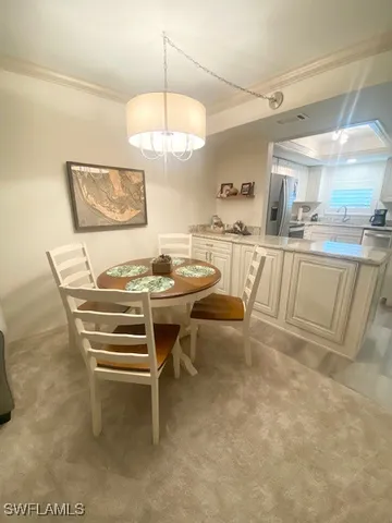 a view of a dining room with furniture a chandelier and kitchen view