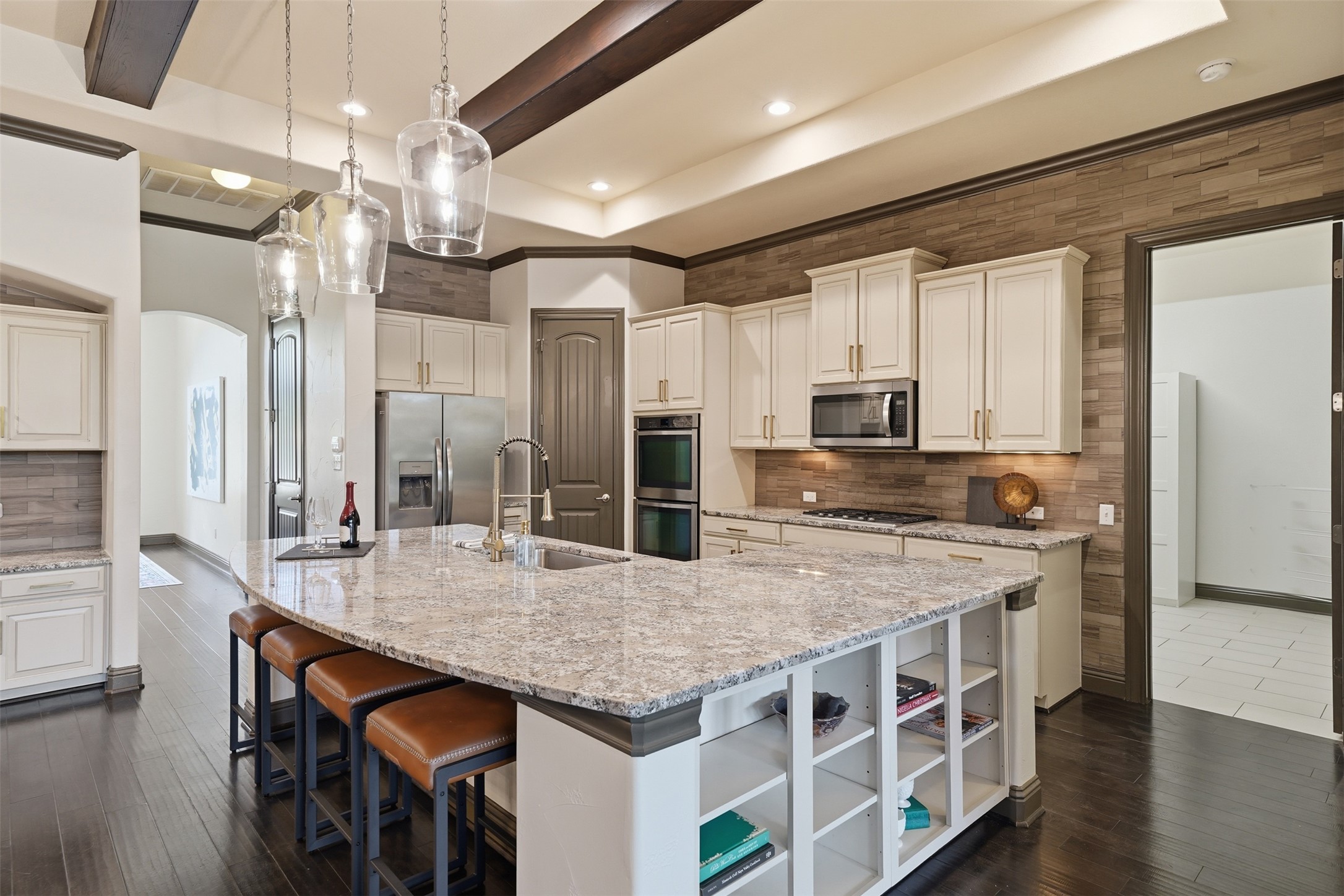 8729 Vantage Point Drive Austin, TX 78737 - Photo 15 of 33 A well-lit kitchen featuring an expansive granite-topped island with casual seating, complemented by dark wood flooring.