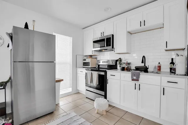 a kitchen with white cabinets and refrigerator