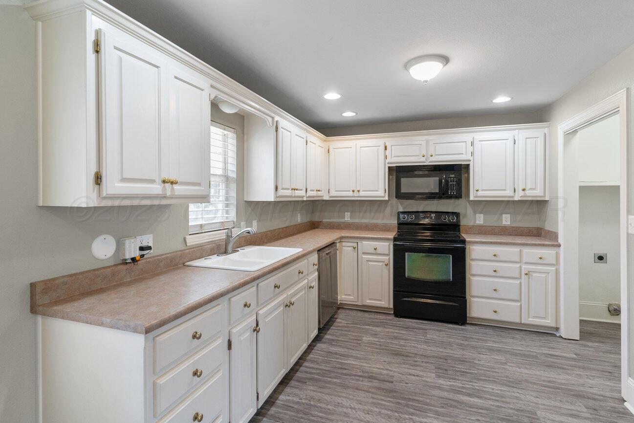 4436 South Travis Street Amarillo, TX 79110 - Photo 8 of 29 a kitchen with sink a microwave and cabinets