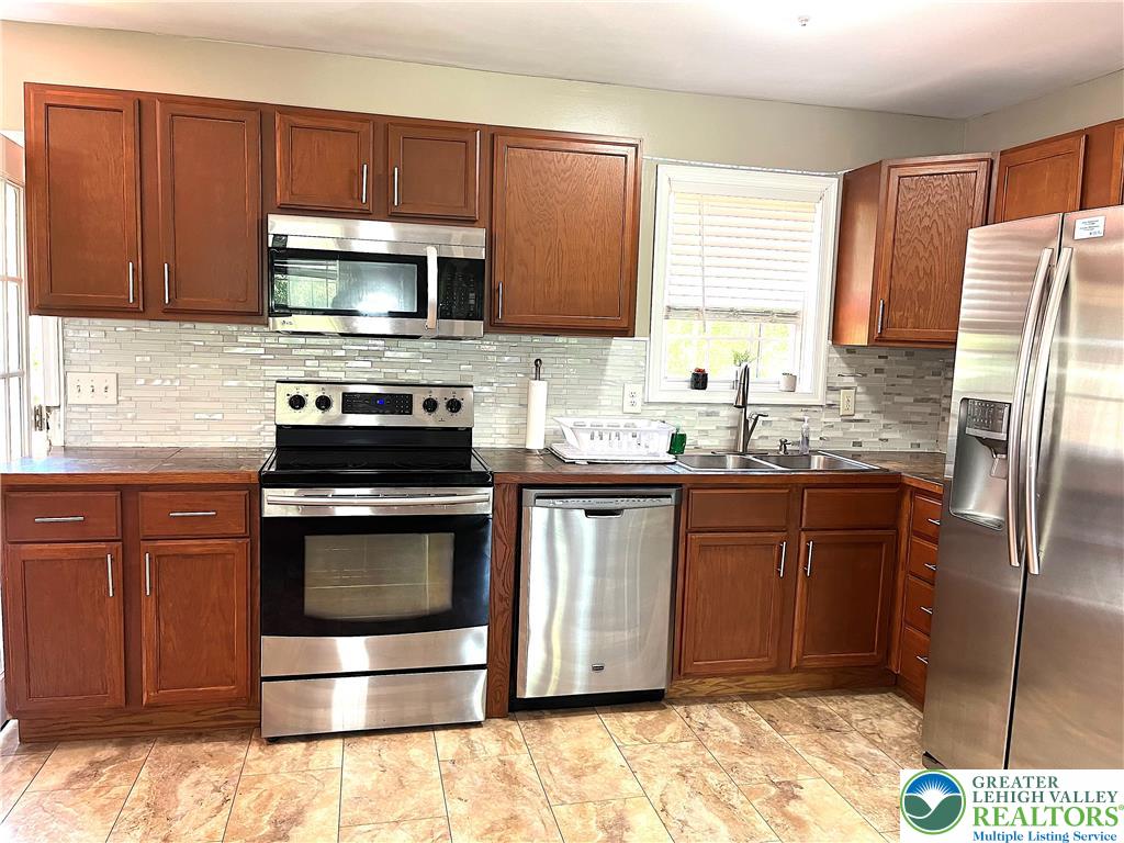 1646 Clover Road Long Pond, PA 18334 - Photo 6 of 24 Rich wood cabinetry surrounds stainless steel appliances set against patterned tile flooring.