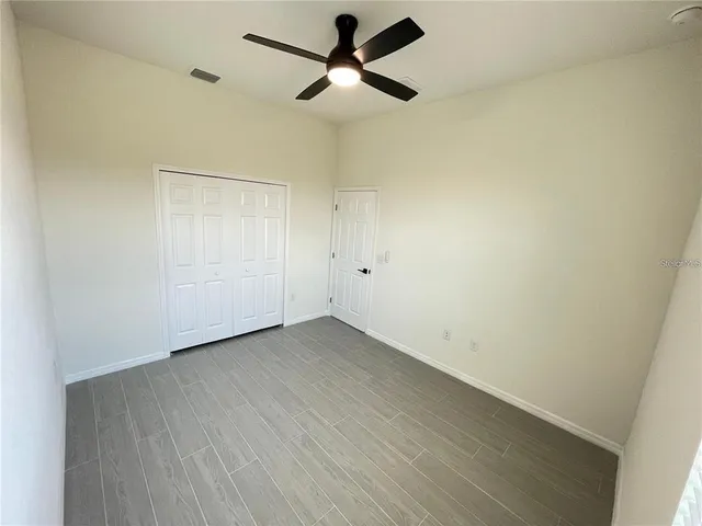 an empty room with a ceiling fan and carpet