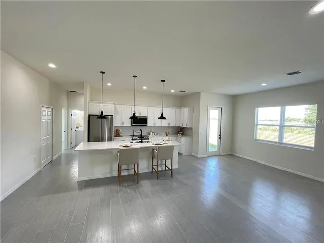 a view of a kitchen with kitchen island a sink wooden floor and a refrigerator