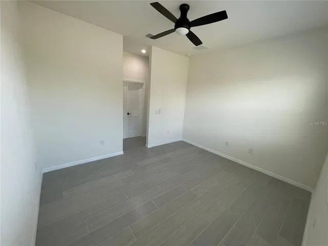 an empty room with a ceiling fan and window