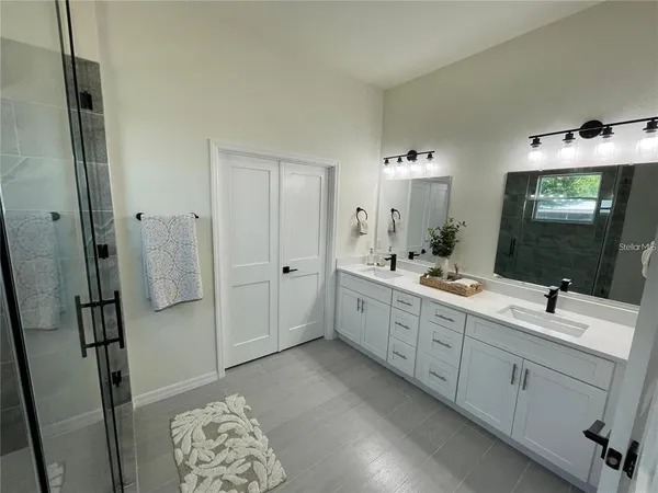 a bathroom with a double vanity sink mirror and shower