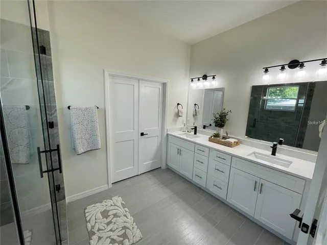 a bathroom with a double vanity sink mirror and shower