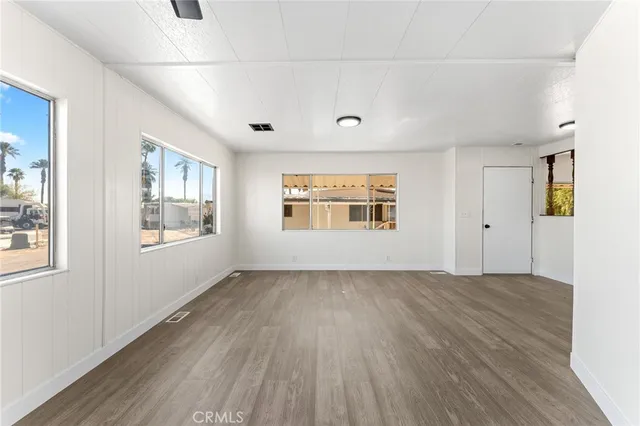 a view of an empty room with a window and wooden floor