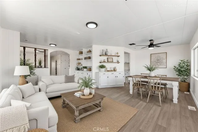 a living room with furniture kitchen view and a wooden floor