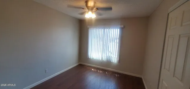 an empty room with wooden floor chandelier fan and windows